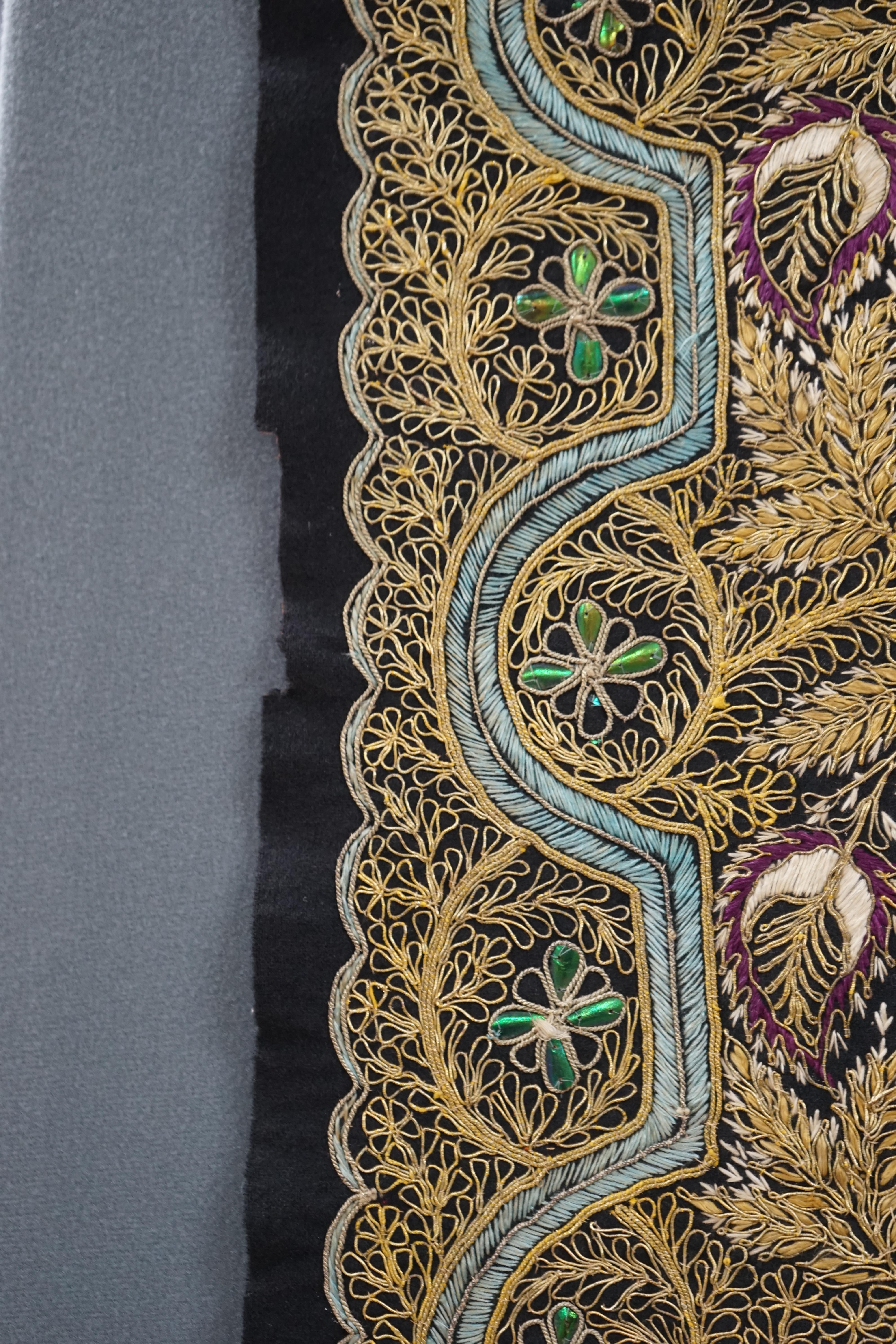 An Indian black felt panel embroidered with mostly gold thread, some coloured silks and beetle wing ornamentation, possibly a border to a larger panel, 256cm long. Condition - good